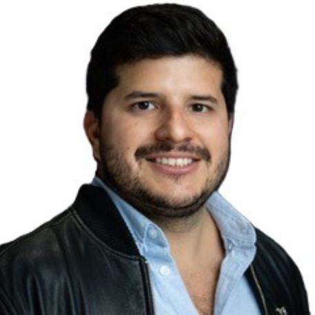 A man with short dark hair and a beard, wearing a black leather jacket over a light blue shirt, smiles at the camera against a plain white background, representing Renal Associates.